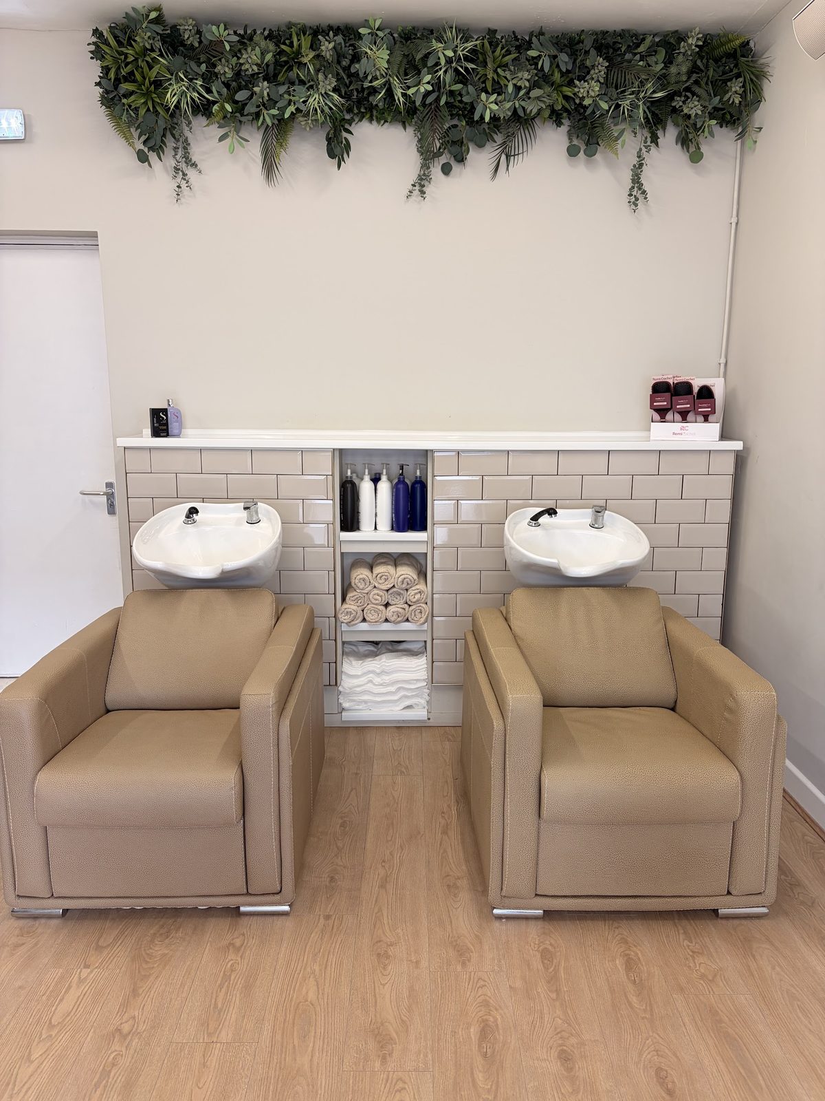 Two backwash chairs beneath a eucalyptus garland