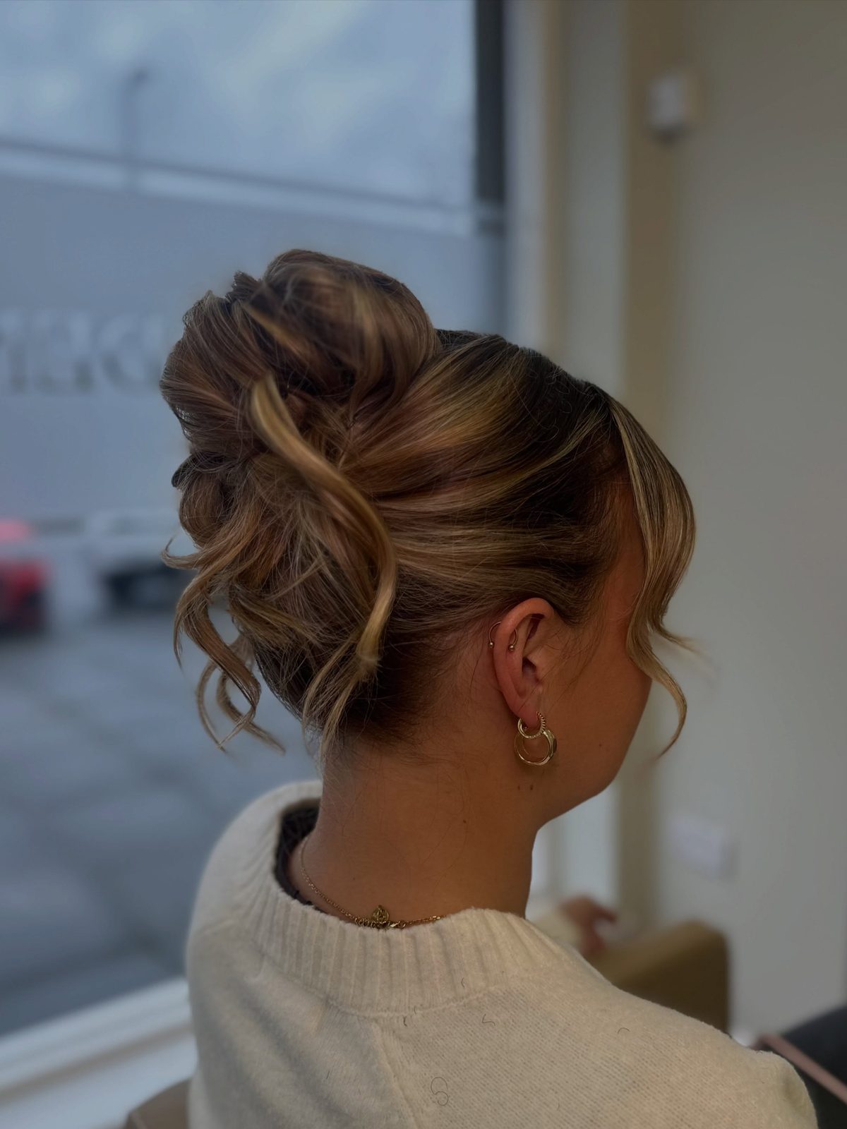 A messy high bun with face-framing pieces, by Ellie