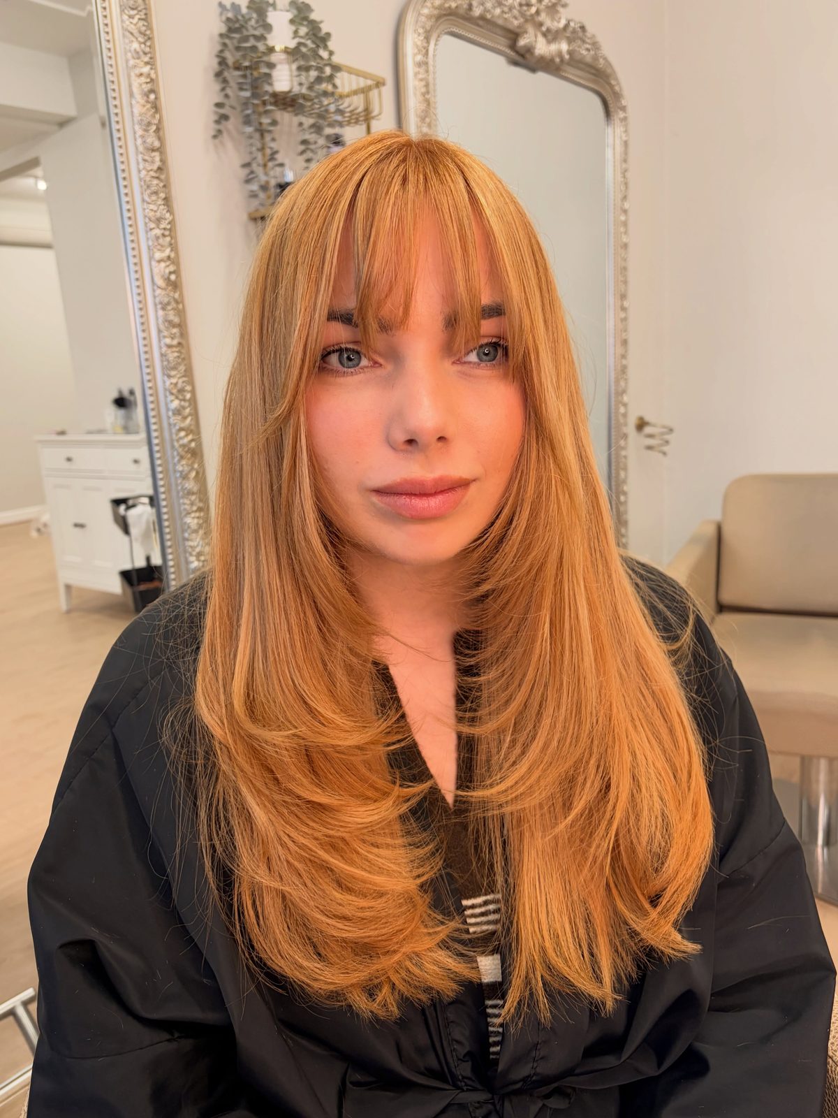 Strawberry blonde hair with a curtain fringe and long layers, front view